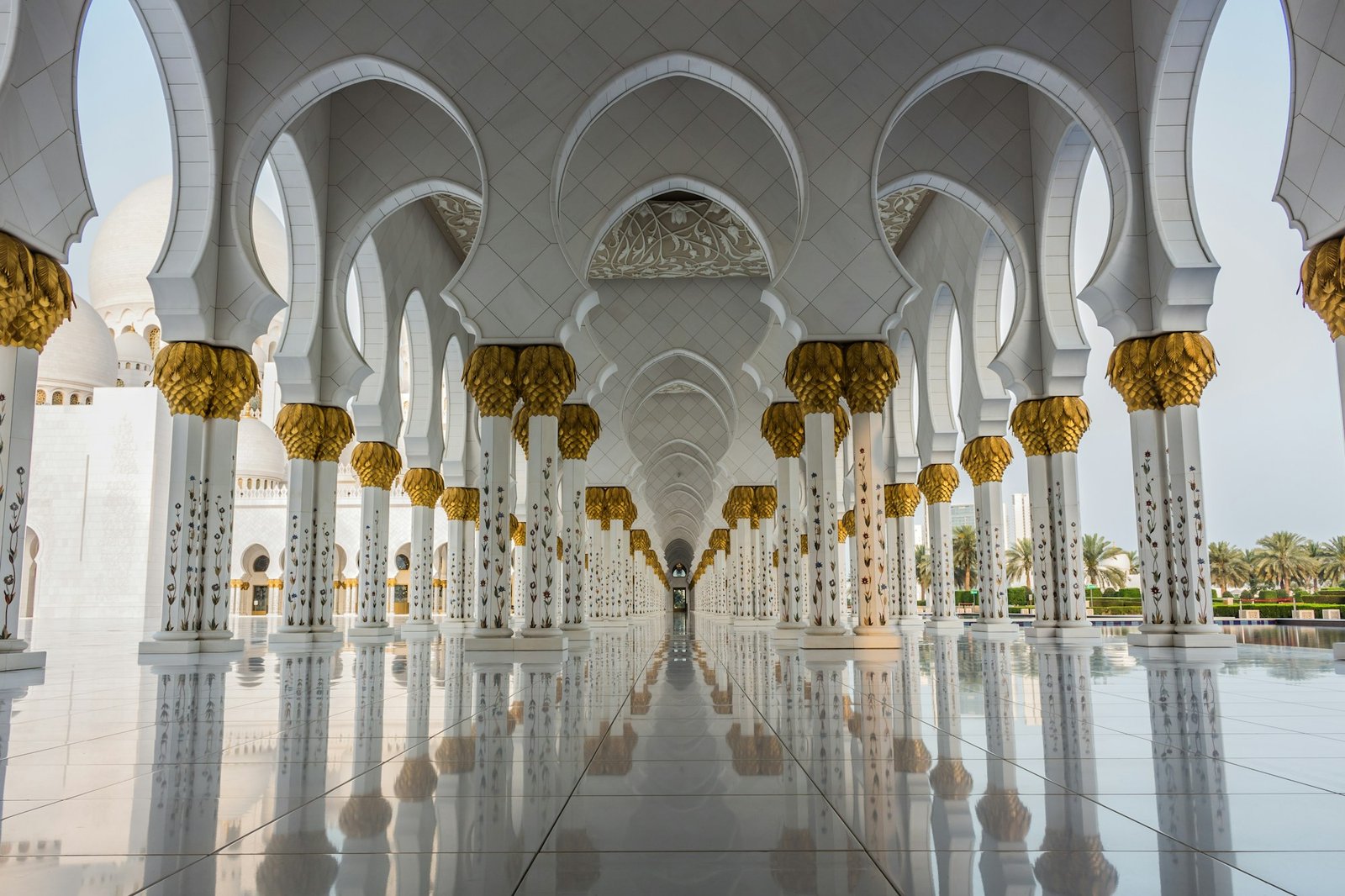 Rows of white arches and golden columns reflected on a marble floor