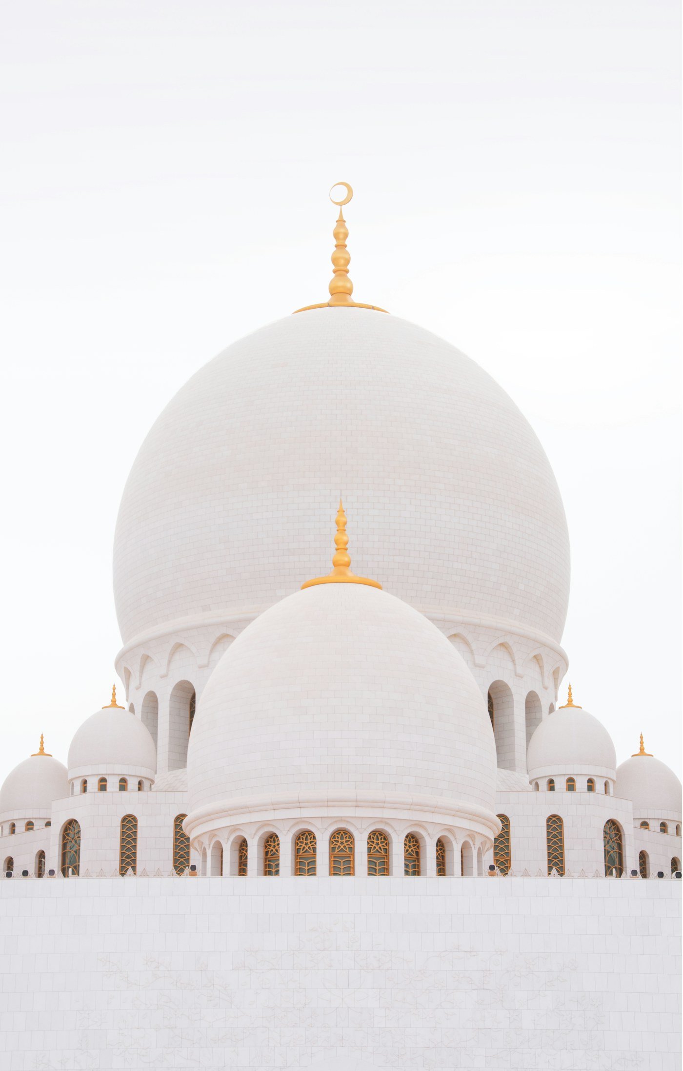 White mosque domes with golden finials in soft light