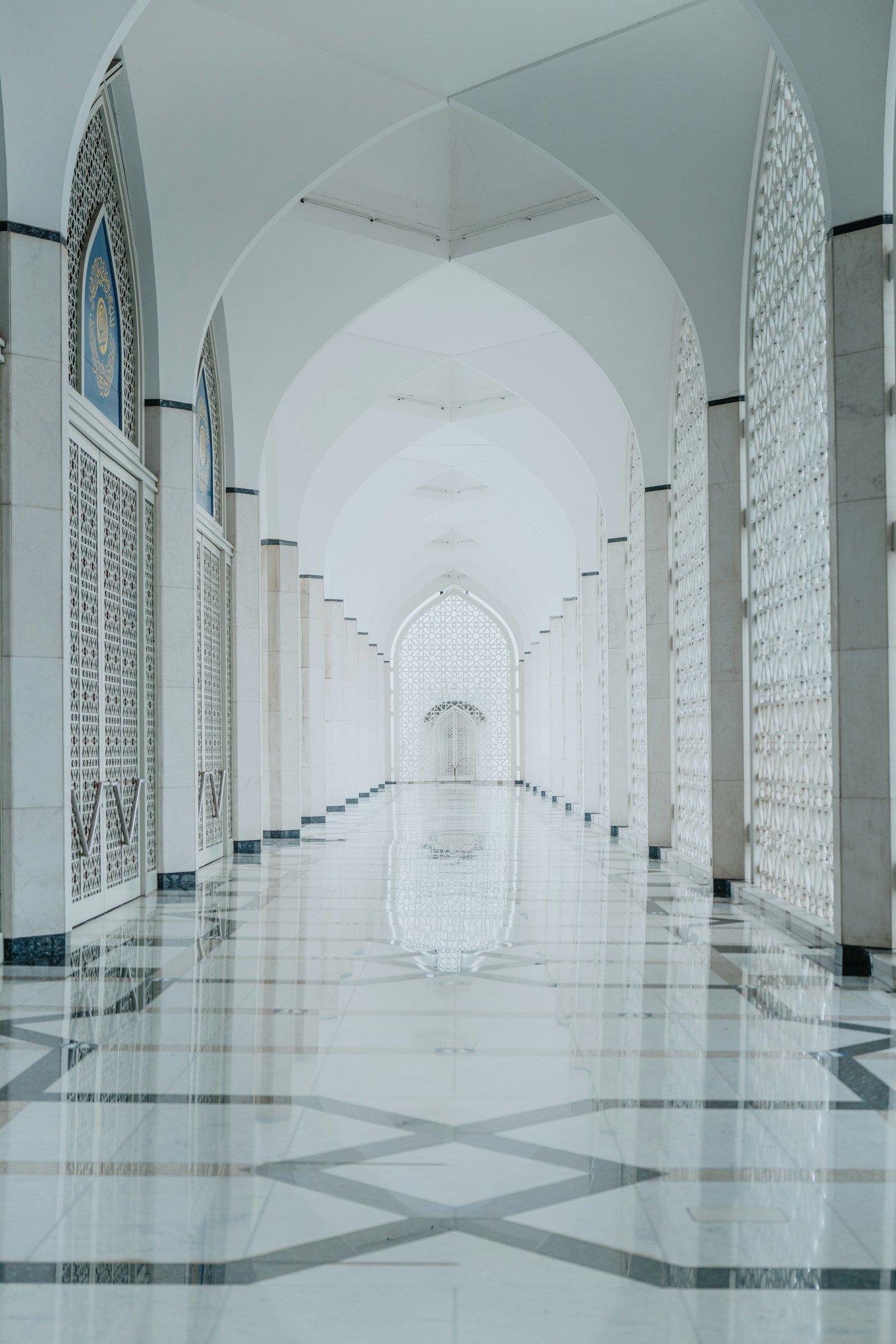 A long white mosque hallway with a patterned marble floor