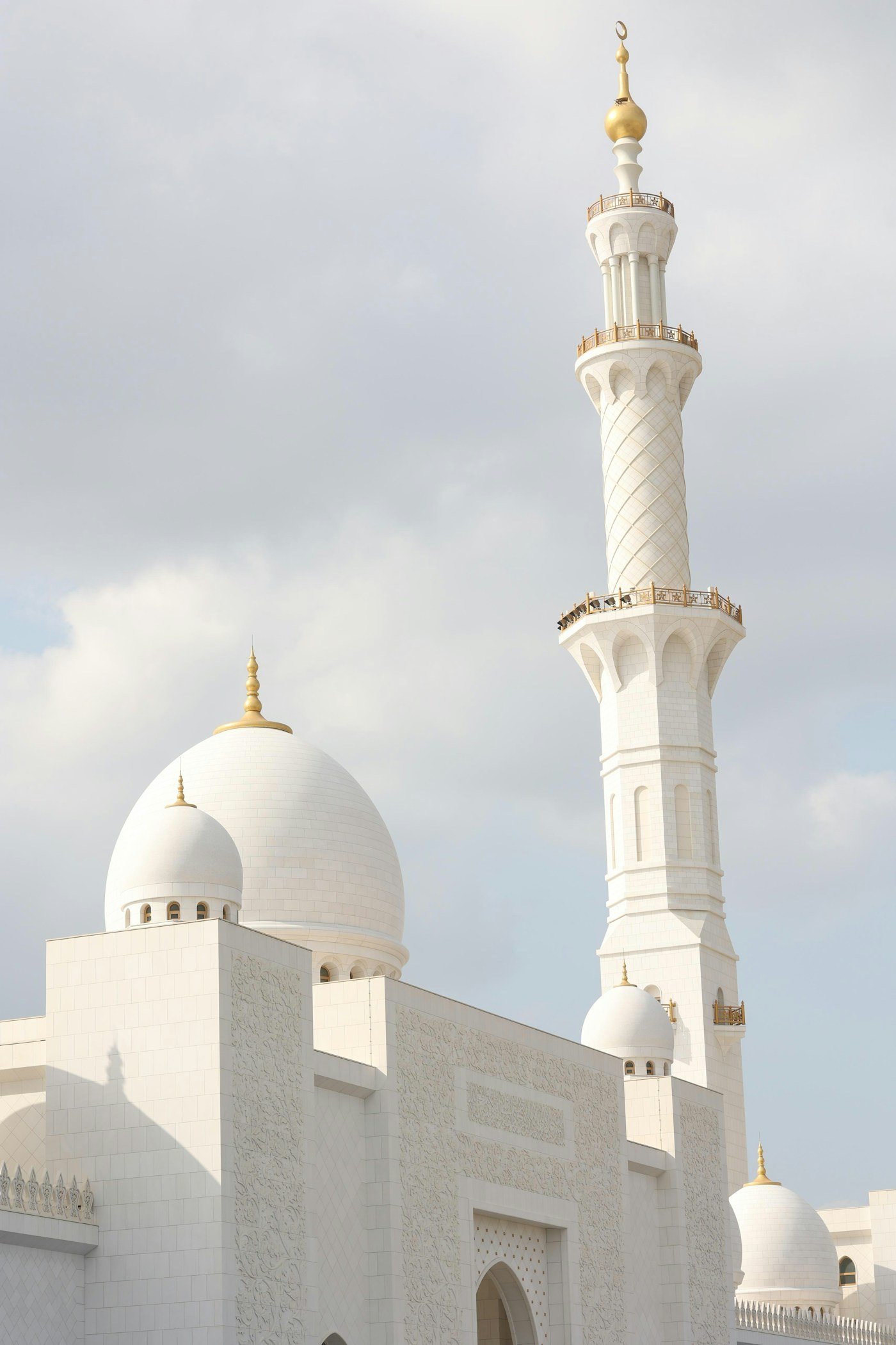 A white mosque with a tall minaret under a bright sky