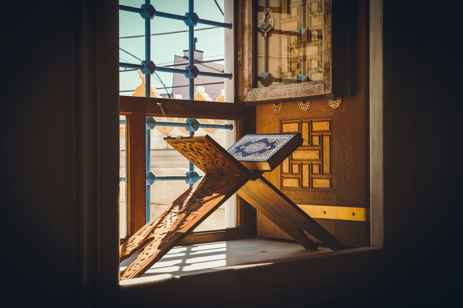 A Quran on a wooden stand by a sunlit window